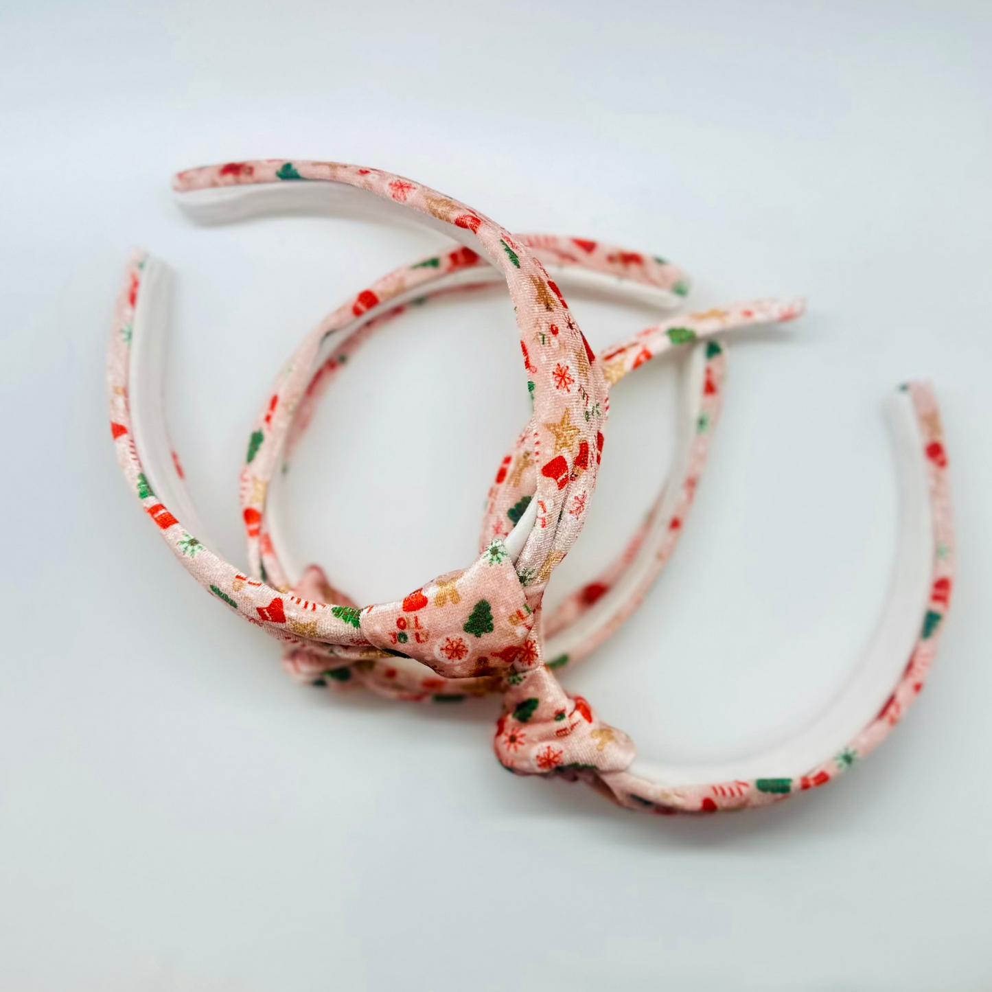 Pink velvet headband with gingerbread men, candy canes, trees, and snowflakes pattern