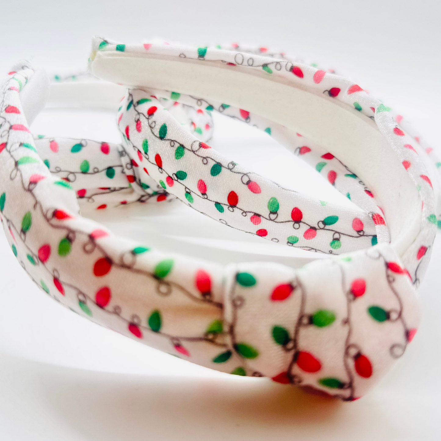 White velvet headband with red, green, and pink Christmas light pattern and knotted top