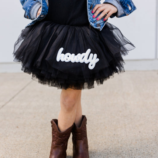 black tutu with white howdy patched tutu with a girl wearing a black tshirt with jean jacket and cowgirl boots.