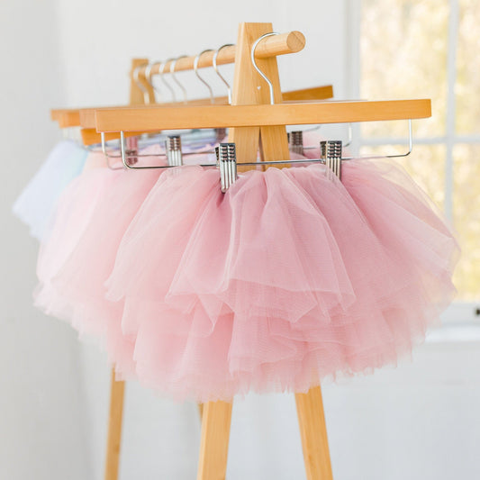 Girls dusty mauve pink tutu skirt for toddlers and kids, fluffy layered tulle ballet skirt for birthdays, parties, dress up, and special occasions, hanging on wooden clothing rack.