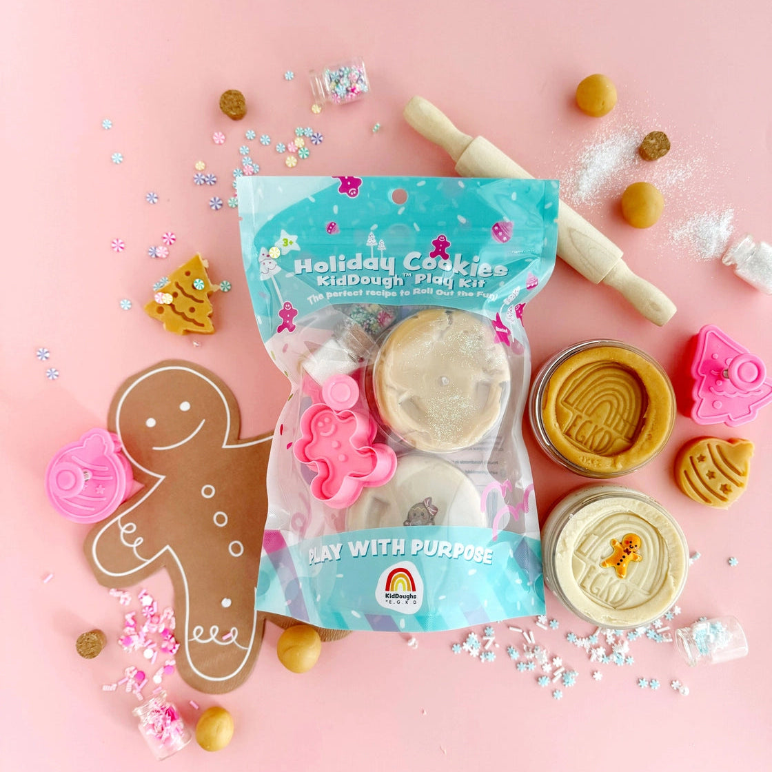 Holiday cookies kid dough play kit with cookie cutters and sprinkles on a pink background