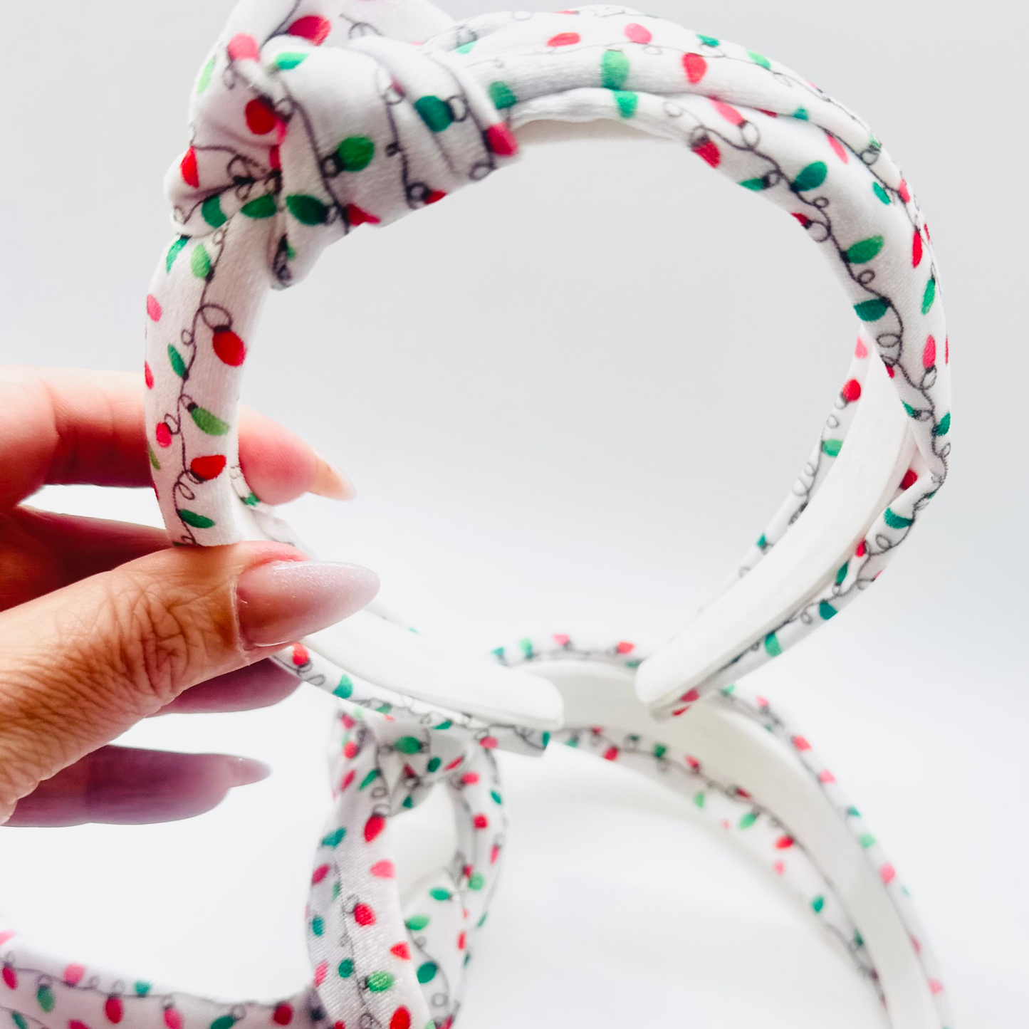 White velvet headband with red, green, and pink Christmas light pattern and knotted top