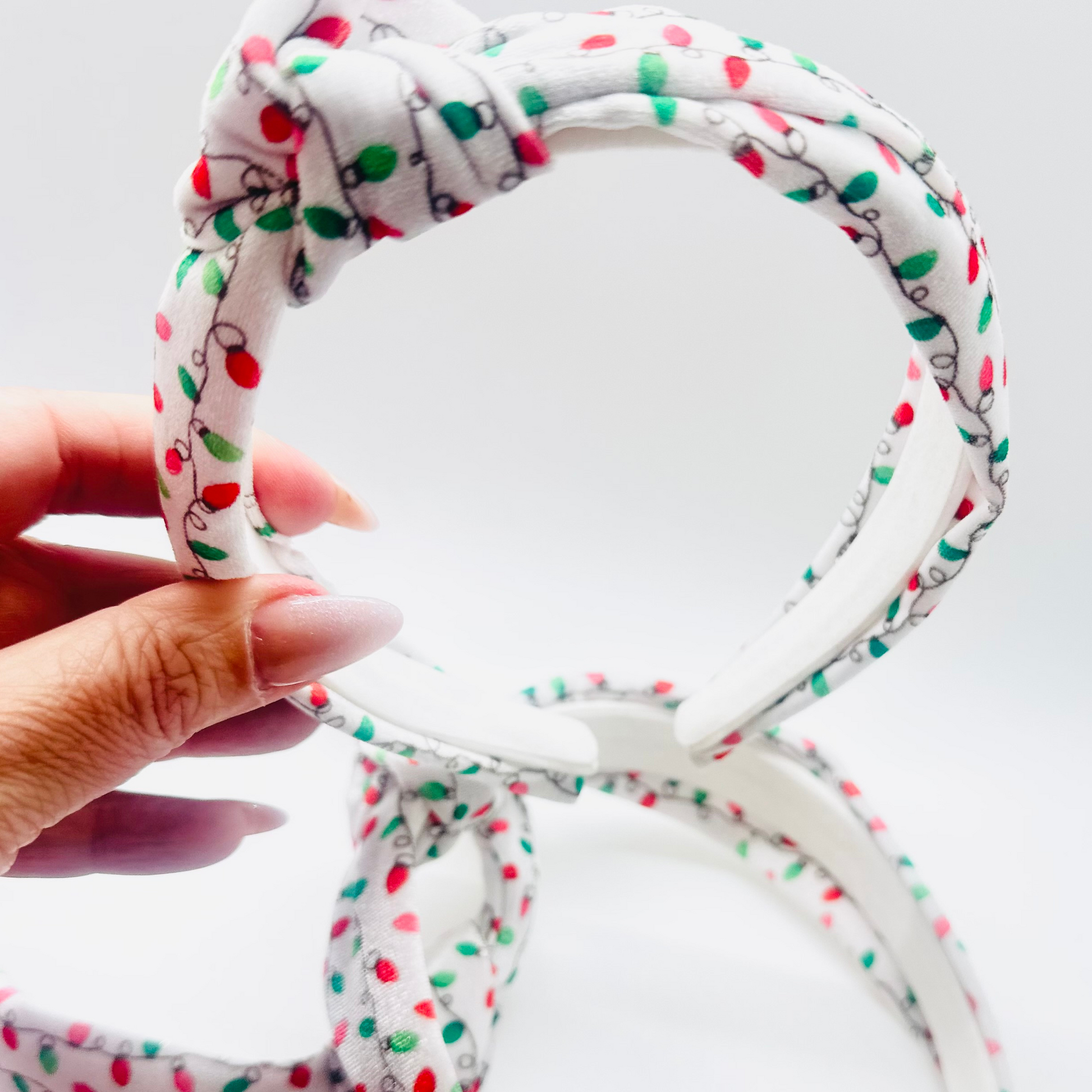 White velvet headband with red, green, and pink Christmas light pattern and knotted top