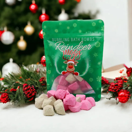 Green packaging of 'Reindeer Magic' bubbling bath bombs with bath bombs in front, Christmas tree in the background