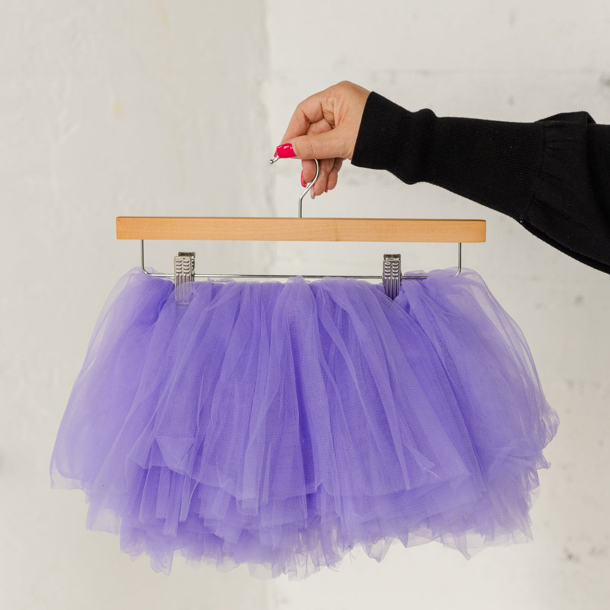 Lavender Purple Tulle tutu shown on a wood hanger with a white wall background