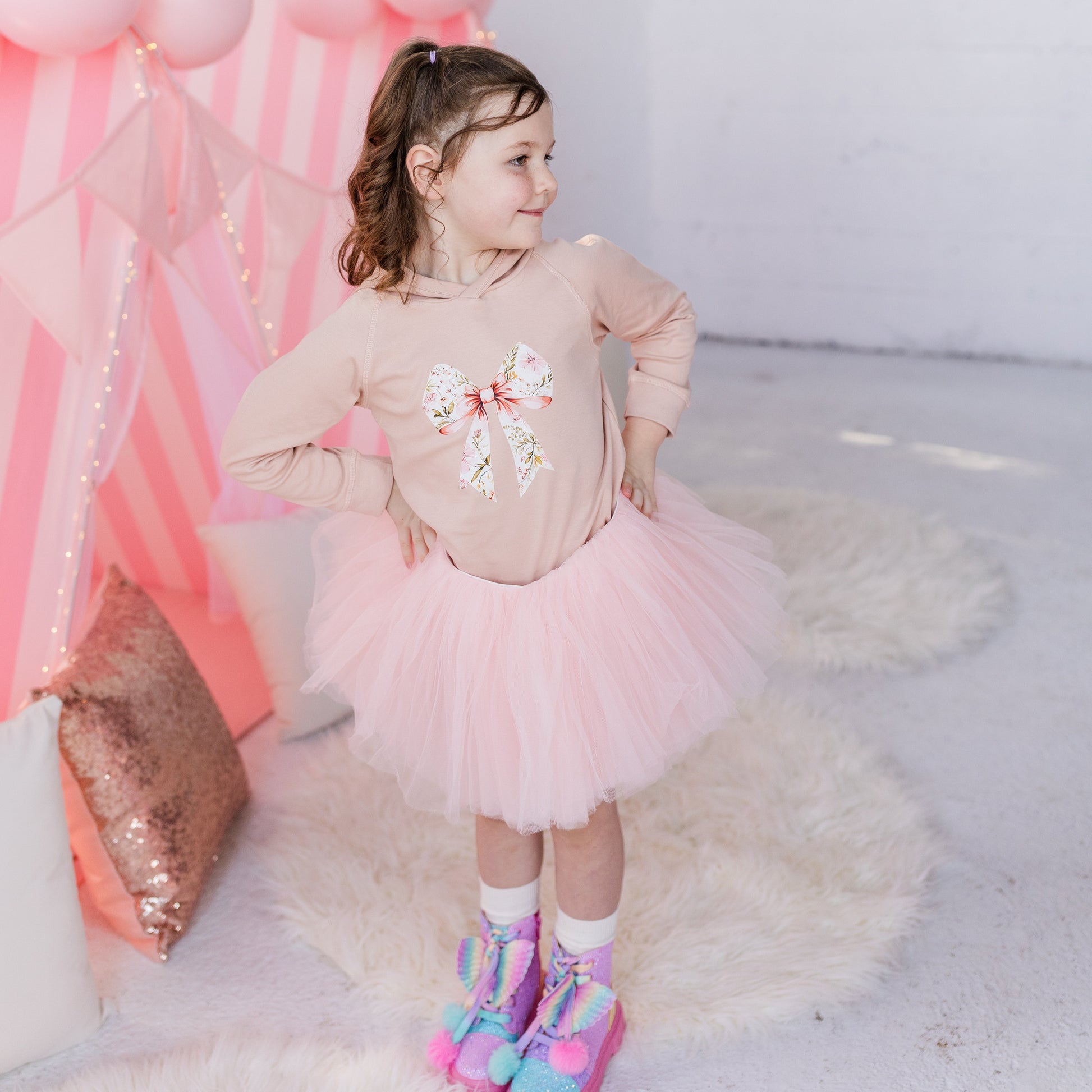 Child in a pink outfit with a balloon arch in the background