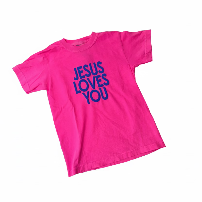 Pink t-shirt with 'Jesus Loves You' text on a gray background