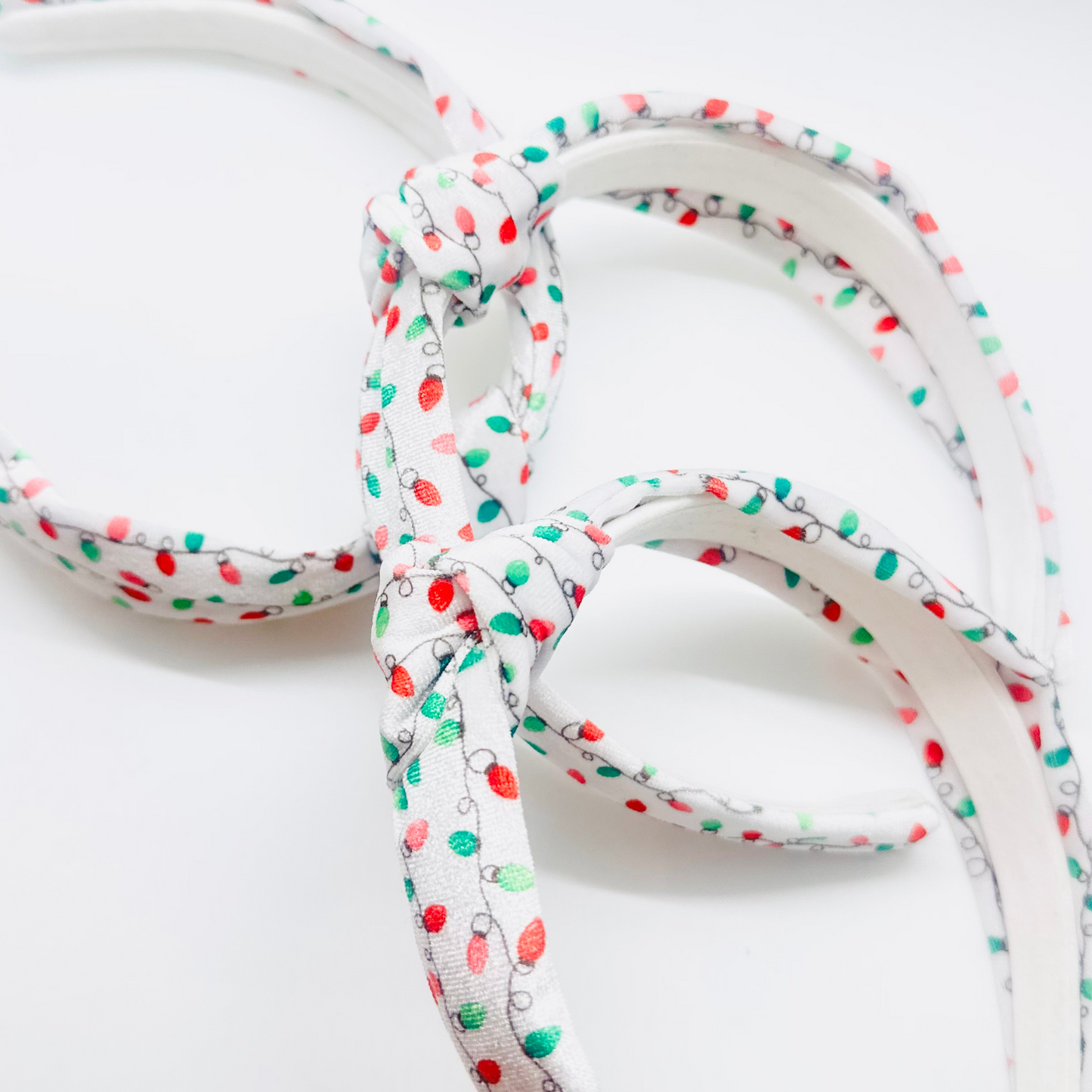 White velvet headband with red, green, and pink Christmas light pattern and knotted top