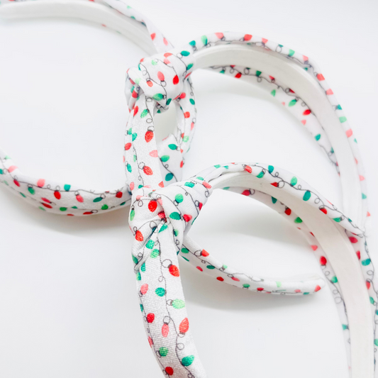 White velvet headband with red, green, and pink Christmas light pattern and knotted top