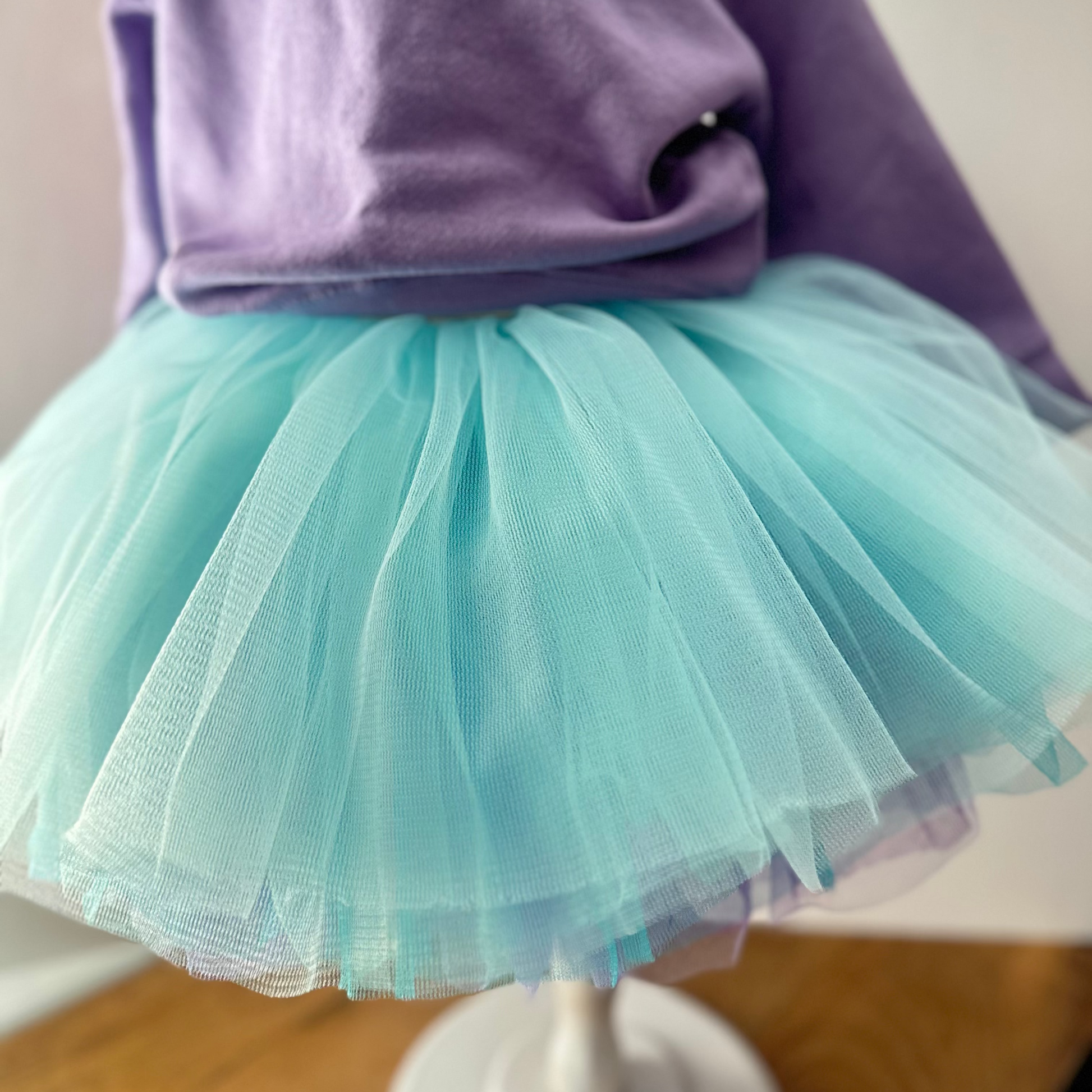 Mannequin wearing a purple top and light blue tutu skirt on a plain background