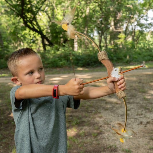 Child holding a bow and arrow in a forest setting